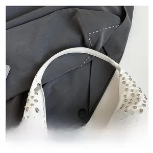 Detail of white moon bag with metallic silver studs and premium leather texture