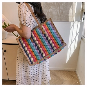 Detailed side view of large rainbow woven straw tote bag with brown leather handles