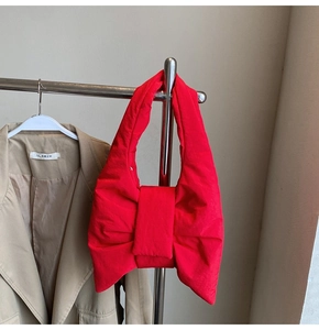 Detail of red oversized bow shoulder bag on a hanger with fashion blazer background