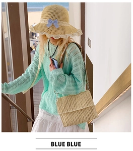 Detail of handwoven straw crossbody bag styled with a mint green knit sweater and beach hat