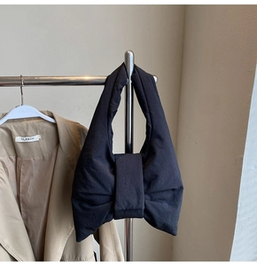 Close-up of a black oversized bow tote bag hanging on a rack with premium fabric texture