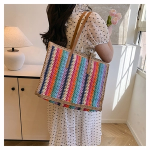 Detail of colorful striped woven tote bag with brown leather straps shown on shoulder