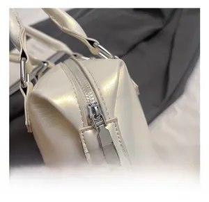 Close-up of premium silver metal zipper and hardware on a creamy pearl white handbag