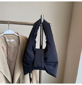 Detail view of the black puffy oversized bow shoulder bag on a hanger with office attire