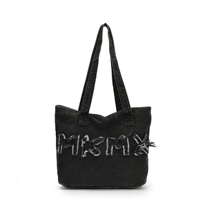 Detail van de zwarte denim tote bag met gerafelde HKMX letters en gewassen textuur