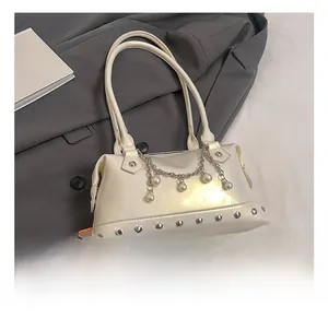 Detail showing pearl chain and silver rivet accents on a creamy white handbag
