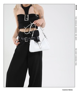 Détail d'un sac bandoulière en cuir blanc avec rivets argentés de style punk et garnitures