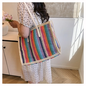 Close-up of a colorful rainbow straw tote bag featuring bohemian woven stripes and white handle