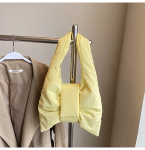 Detail of light yellow nylon tote bag featuring a padded bow design and quilted texture
