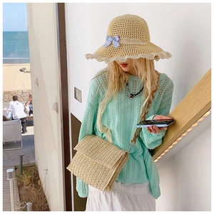 Close-up of summer straw crossbody bag paired with knitwear and a lace-trim sun hat