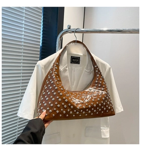 Detail view of brown underarm bag with silver stud accents and glossy finish