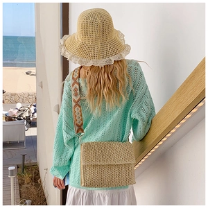 Detail of summer straw bag with ethnic embroidered strap shown in beach vacation setting