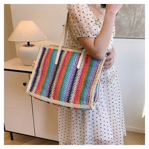 Detail of the rainbow striped straw tote bag with a focus on woven texture and slim straps