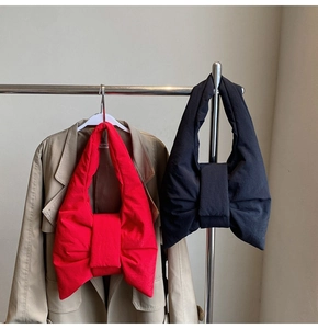 Detail of red and black oversized bow shoulder bags with a padded puffy texture