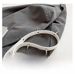 Gros plan sur la bandoulière en cuir blanc avec rivets métalliques argentés et couture