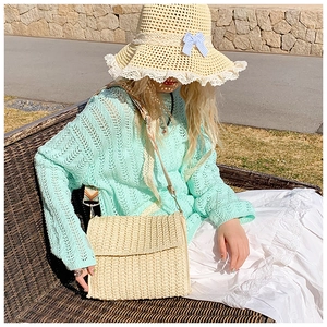 Close-up of beige woven straw shoulder bag with natural texture and matching woven strap