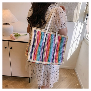 Close-up of a large striped crochet tote bag with white shoulder straps on a model