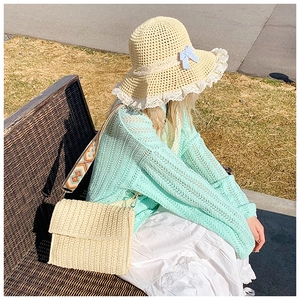 Detail of straw hat with lace trim and woven crossbody bag with geometric strap