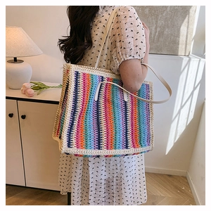 Detail of colorful rainbow woven straw tote bag with cream straps in a boho setting