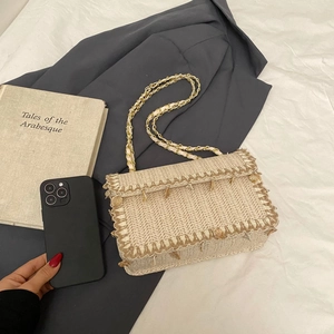 Handwoven straw shoulder bag with gold chain strap and decorative pendant for vacation