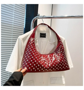 Macro detail of red hobo bag featuring polished faux leather and silver stud embellishments