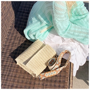 Detail of bohemian straw bag featuring a colorful embroidered wide jacquard shoulder strap