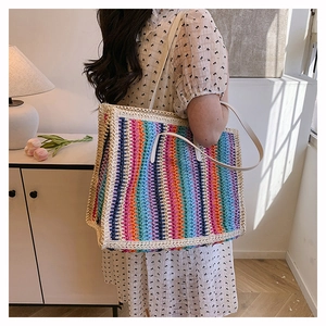 Close-up of rainbow striped straw tote bag on a model's shoulder for daily commute