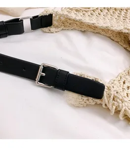Detail of silver metal buckle on black leather strap of beige handmade knit tote bag