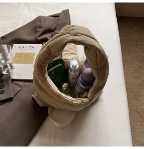 Detailed interior view showing high capacity of beige padded nylon hobo bag on white bedding