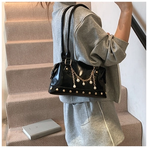 Detail of black patent leather tote with gold studs, pearl charms, and chain strap