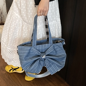Large denim tote bag with oversized bow and butterfly charm shown in lifestyle setting