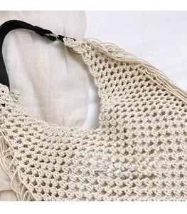Close-up of cream woven shoulder bag featuring fringe detail and black leather strap
