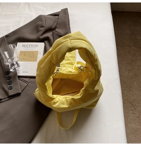 Detailed top view of a bright yellow padded tote bag with metallic buckle detail