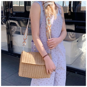 Detail of bohemian straw shoulder bag with colorful geometric patterned woven strap