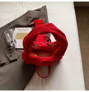 Detail of red quilted tote bag with wide handle and metal hardware for strap attachment