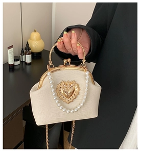 Detail of beaded handle and golden heart metal clasp on a vintage ivory leather handbag