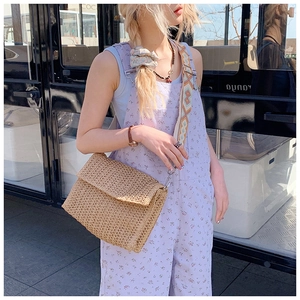 Detail of hand-woven straw crossbody bag with ethnic style jacquard strap and silver clasp