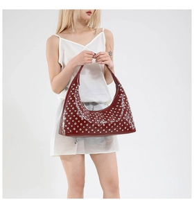 Macro detail of glossy burgundy leather hobo bag with silver metallic stud rivets