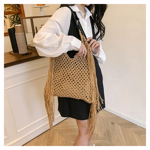 Detail of handmade woven tote bag with hollow mesh design and long bohemian side fringes