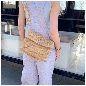 Detail of beige woven straw crossbody bag with patterned geometric shoulder strap