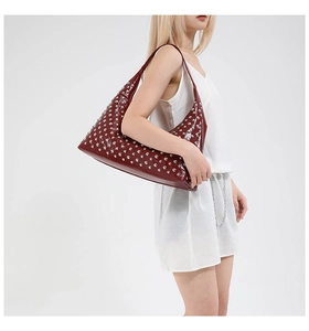 Detail of burgundy hobo shoulder bag featuring vintage silver rivet studs on glossy leather