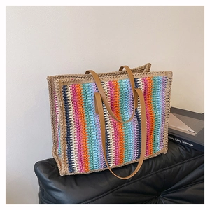 Close-up of rainbow striped straw tote bag with vertical weave and brown leather handles