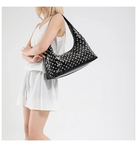 Detail of black Hobo bag featuring silver rivets and glossy patent leather finish