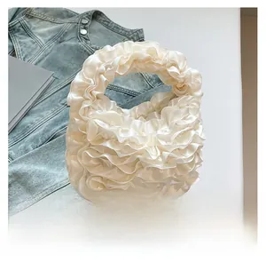 Detailed view of cream ruffled handbag featuring elegant satin layered flower pleats