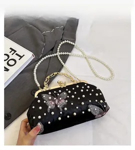 Détails d'un sac de soirée en velours noir avec broderie papillon et perles d'ornement