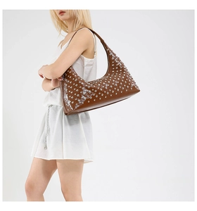 Detail of dark brown leather hobo bag featuring decorative silver metal rivets and studs