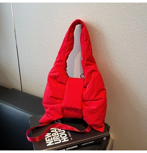Detailed view of red padded nylon tote bag with bow design on a dark sofa surface