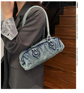 Close-up of vintage blue denim shoulder bag with metal studs and curved stitching