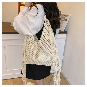Detailed side view of beige hand-woven tote bag with elegant long side tassels