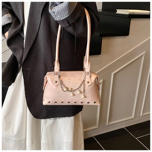 Detail of light pink leather tote bag featuring pearl chains and silver rivet studs